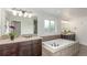 Bathroom displays soaking tub with stone surround, dual sink vanity with granite counter, and bright natural light at 3322 W 26Th Ave, Denver, CO 80211