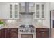 Close-up of the stove and range hood in this kitchen with tile backsplash and granite countertops at 3322 W 26Th Ave, Denver, CO 80211