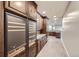 Hallway featuring rich wood cabinetry, built-in coolers, stone countertops, and light wood floors at 770 International Isle Dr, Castle Rock, CO 80108
