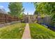 Lush backyard featuring grass, a stone path, and brick house exterior at 2435 N Irving St, Denver, CO 80211