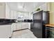 Compact kitchen featuring white cabinetry, black countertops, black appliances, and bright natural light at 2849 W Vassar Ave, Denver, CO 80219