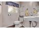 Well-lit powder room featuring pedestal sink, wood-look floors, and window with blue valance at 105 Hawthorn St, Frederick, CO 80530