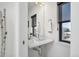 Modern bathroom with a sleek vanity, decorative mirror, and a bright window at 4214 E 8Th Pl, Denver, CO 80220