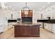 A modern kitchen features custom cabinets, backsplash, large center island, and designer chandelier at 8680 Summerlin Pl, Longmont, CO 80503