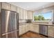 Well-lit kitchen featuring stainless steel appliances, granite countertops, bright cabinets, and a window view at 6150 S Southwood Dr, Centennial, CO 80121