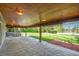 Spacious covered patio featuring wood ceiling, lighting, concrete floor, and view of the large lawn at 6150 S Southwood Dr, Centennial, CO 80121