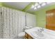 Bathroom featuring vibrant green walls, a polka dot shower curtain, and wood cabinets at 19817 E Prentice Ave, Centennial, CO 80015