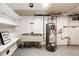 Basement laundry room with vintage utility sink, storage shelves, and modern water heater at 1945 Yosemite St, Denver, CO 80220