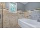Bright bathroom with tiled walls, a bathtub, and towel racks at 7900 E Iowa Ave, Denver, CO 80231