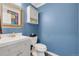Chic powder room with a modern vanity, ornate mirror, and stylish fixtures complementing the vibrant blue walls at 7900 E Iowa Ave, Denver, CO 80231