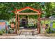 Entrance to the community garden with a wooden archway, garden beds, and information signs at 46 S Perry St, Denver, CO 80219
