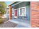 Inviting covered front porch featuring a red front door, brick columns, and outdoor seating area at 1444 S Richfield Way, Aurora, CO 80017