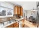 Kitchen featuring wood cabinets, stainless steel sink, and dining area access at 1444 S Richfield Way, Aurora, CO 80017
