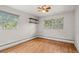 Bright bedroom featuring hardwood floors, neutral walls, ceiling fan, and windows with lush outdoor views at 7350 Field St, Arvada, CO 80005