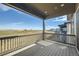 A covered back porch with wood railing overlooks an open field and a pond at 2978 Newfound Lake Rd, Berthoud, CO 80513