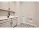 Bright laundry room featuring a sink, cabinets, and a stylish patterned tile floor at 2978 Newfound Lake Rd, Berthoud, CO 80513