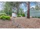 Serene backyard with mature trees, dry creek bed, and bridge leading to a quaint backyard feature at 881 S Pearl St, Elizabeth, CO 80107