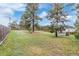 Expansive fenced backyard featuring a lush lawn, mature trees, and a charming windmill feature at 881 S Pearl St, Elizabeth, CO 80107