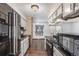 View of kitchen featuring black appliances, white cabinets, and wooden flooring that leads to a living space at 881 S Pearl St, Elizabeth, CO 80107