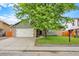 Charming home featuring a well-manicured lawn, brick accents, mature tree, and an attached two-car garage at 915 S Mckinley Ave, Fort Lupton, CO 80621