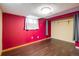 Finished basement with wood-look floors, built-in closet space, and a brightly painted accent wall at 7210 Otis Ct, Arvada, CO 80003