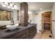 Bathroom with dual sinks, stone countertops, wood cabinets and a door to a private sauna at 7210 Otis Ct, Arvada, CO 80003