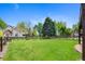 Large backyard with wooden fence, deck, and mature trees, perfect for outdoor enjoyment at 42 Blue Sage, Littleton, CO 80127