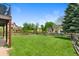 Large backyard with wooden fence and mature trees, visible from the deck at 42 Blue Sage, Littleton, CO 80127