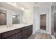 Bathroom featuring a double vanity, dark cabinets, and a glass-enclosed shower at 1376 Lumber Ridge N Cir, Erie, CO 80516