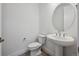 Modern powder room featuring a pedestal sink, round mirror, and a sleek toilet at 1376 Lumber Ridge N Cir, Erie, CO 80516