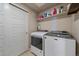 Functional laundry room with new washer and dryer units, shelving, and neutral walls at 420 E Fremont Pl # 203, Centennial, CO 80122