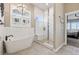 Bright bathroom featuring a soaking tub, a window with shutters, and a glass enclosed shower at 2932 Heron Lakes Pkwy, Berthoud, CO 80513
