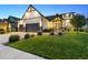 Home exterior featuring a manicured front lawn, landscaped garden beds, and a spacious three-car garage at 2932 Heron Lakes Pkwy, Berthoud, CO 80513