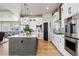 Bright kitchen featuring white cabinets, stainless steel appliances, and a large gray island with pendant lighting at 2932 Heron Lakes Pkwy, Berthoud, CO 80513