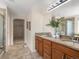 Bathroom with double sink vanity, wood cabinets, granite counters, tile floors, and a large mirror at 7812 Blue Water Ln, Castle Rock, CO 80108