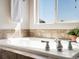 Close-up of a luxurious soaking tub with tile surround and chrome fixtures under a sunny window at 7812 Blue Water Ln, Castle Rock, CO 80108