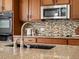 Close-up of a kitchen sink with granite countertop, modern faucet, mosaic backsplash, and stainless steel appliances at 7812 Blue Water Ln, Castle Rock, CO 80108