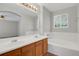 Large bathroom with double vanity, soaking tub and window, with tile surround and wood-look flooring at 9690 Lansing Cir, Commerce City, CO 80022