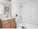 Bright bathroom featuring white tiled walls, wooden vanity, and a shower-tub combo at 5991 W 68Th Ave, Arvada, CO 80003