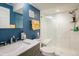 Modern bathroom featuring a glass shower, vanity with marble top, and blue accent wall at 1038 Petras St, Erie, CO 80516