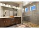 Modern bathroom featuring a double vanity, large mirror, and a spacious walk-in shower with decorative stone floor at 1794 Wright Dr, Erie, CO 80516