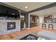 Cozy living room with a stone fireplace, a large TV, and a view into a modern kitchen at 1794 Wright Dr, Erie, CO 80516