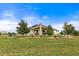 Rear of home with a expansive lawn, stone chimney and mature trees at 17155 Primrose Ln, Mead, CO 80542
