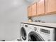 Functional laundry room with modern washer and dryer and overhead storage cabinets at 8977 E Otero Pl, Centennial, CO 80112