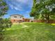 Large backyard with lush green lawn, mature trees, and a patio area ideal for outdoor entertaining at 10371 Monterey Cir, Northglenn, CO 80260