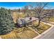 An aerial view of a well-maintained home with a large tree, a paved driveway, and a landscaped yard at 13 Wedge Way, Littleton, CO 80123