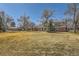 Charming two-story home features a well-maintained lawn, mature trees, and a classic brick facade with blue shutters at 13 Wedge Way, Littleton, CO 80123