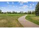 A concrete walking path winds through a large green park, offering a scenic route for exercise and recreation at 6519 Eastview St, Longmont, CO 80504