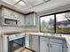 Modern kitchen features stainless steel appliances, bright countertops, and blue cabinets with a view of the yard at 8546 E Mineral Cir, Centennial, CO 80112