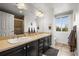 Bathroom with double vanity, dark cabinets, and tiled flooring with a window at 7829 Nile Cir, Arvada, CO 80007